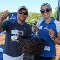 woman and man handing out alumni koozies